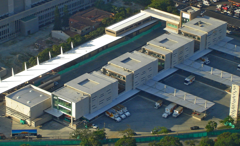 Vista aérea de la plataforma logística TCC en Medellín, Antioquia, con camiones de carga y descarga. Servicios de diseño y construcción por Dinpro.