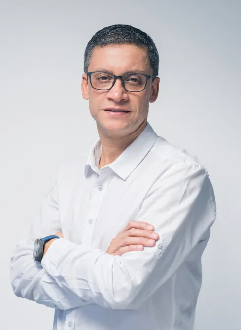 Retrato de Alexander Fernández Franco, Director Administrativo de Dinpro. Imagen profesional de un abogado con camisa blanca y gafas.