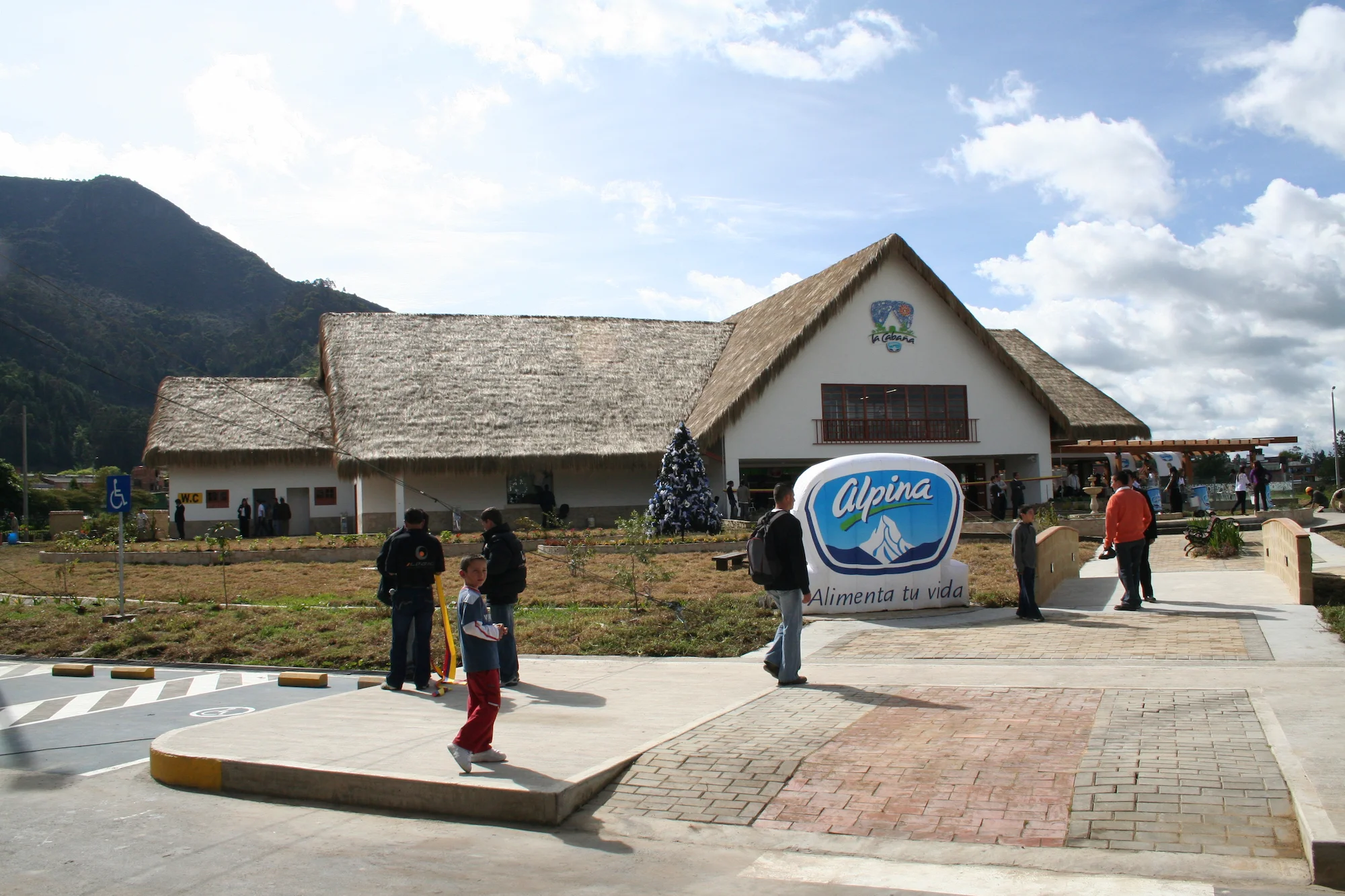 Cabaña Alpina en Sopó, Cundinamarca, diseño arquitectónico para comercio retail. Fachada de cabaña con techo de paja y logo de Alpina.